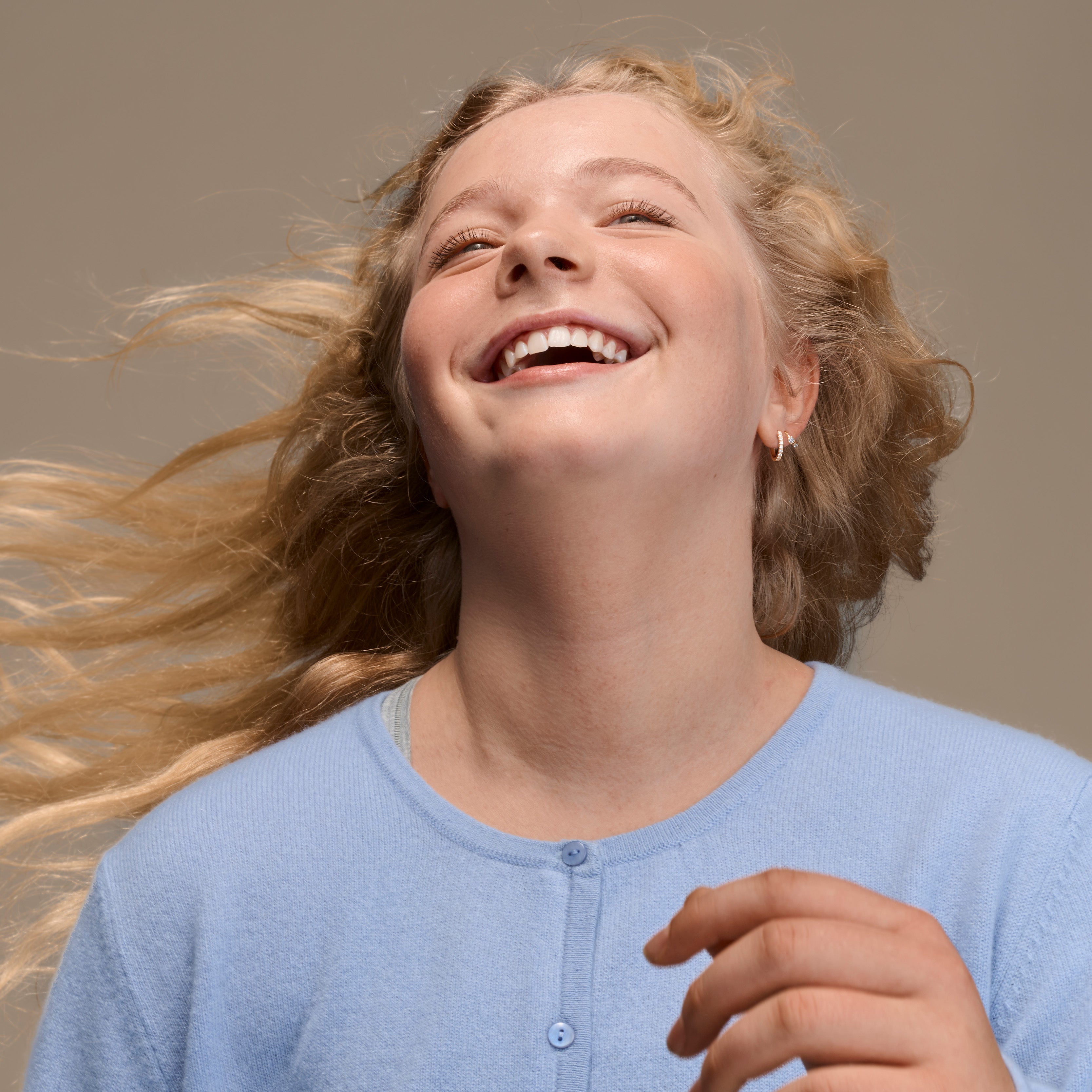 Young girl with blonde hair smiling against a neutral background